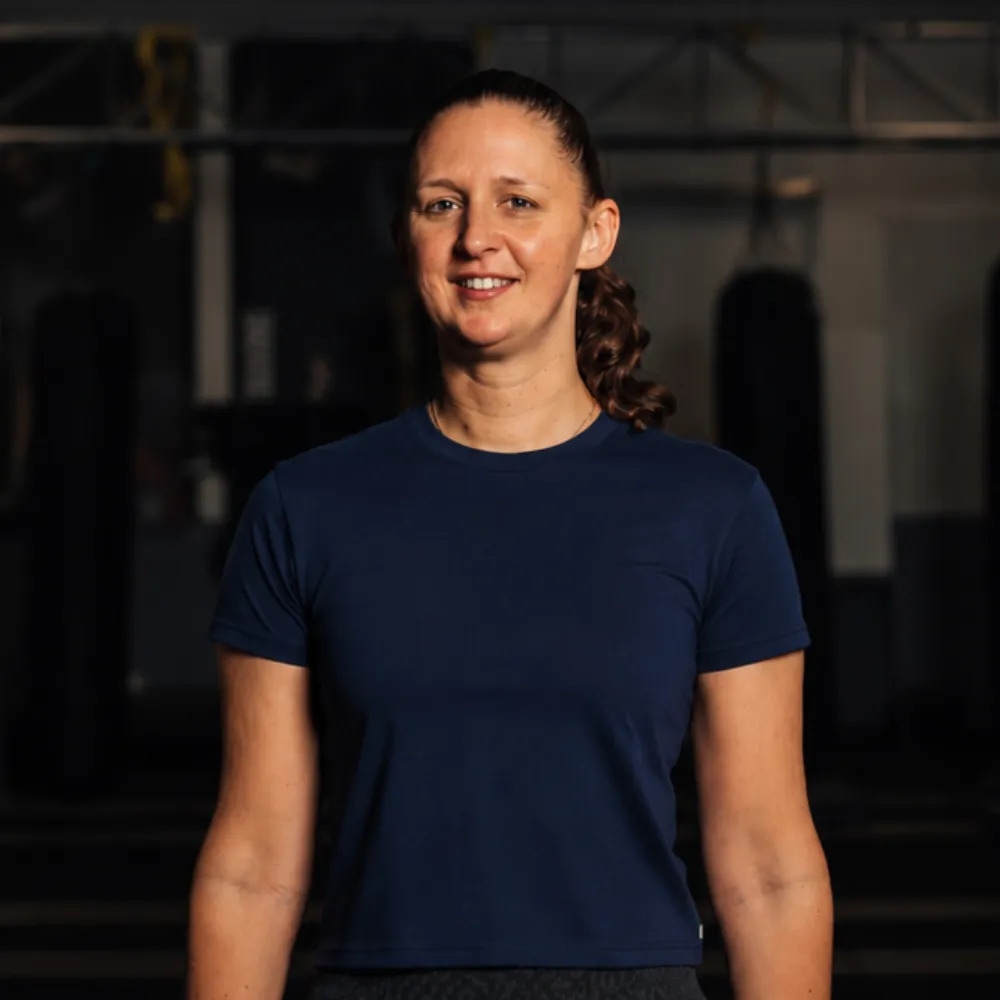 Femme souriante en t-shirt bleu dans une salle de sport